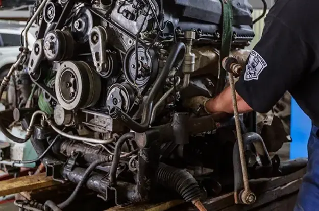 Mechanic working on a diesel engine in a repair shop.